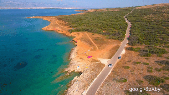 Aerial view of car driving on road beside the sea with view on beaches and coast on a sunny day. Beauty of Croatia.