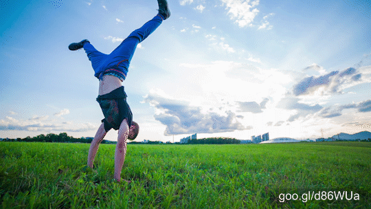 Slow motion landscape shot of young man doing stunts on grass.