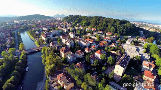 Flying above beautiful city with landscape view of river, castle and green hills.