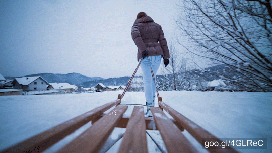  POV of being on wooden sleigh while woman pulling in snow.